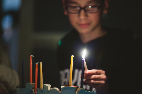 Teenage boy lighting Menorah during Hanukkah