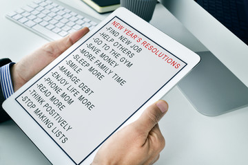 Naklejka na ściany i meble man with a list of new years resolutions in a tablet