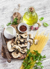 Raw ingredients for cooking pasta with porcini  - dried porcini mushrooms, spaghetti, cream, garlic, parsley, basil, olive oil and spices. On white wooden table. Vegetarian lunch. Healthy food
