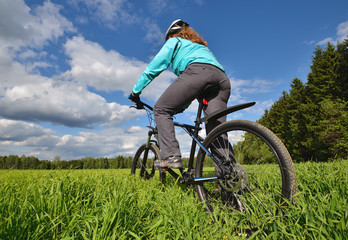 Fototapeta na wymiar woman riding a mountain bike on a background of the blue sky