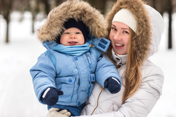 Happy young mother walking with her baby in the park in winter