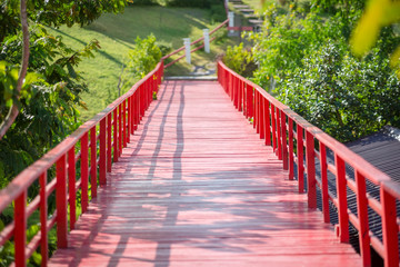 Red wooden bridge over the river in the park.