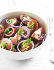 fresh salad with tomatoes in a white bowl on a light surface