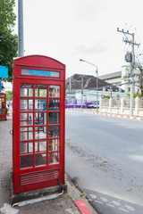 Red box of telephone near the road