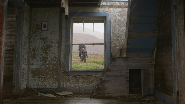 Expeditioners walk by an abandoned house in Hebron, Newfoundland and Labrador on a snowy day. Slow Motion