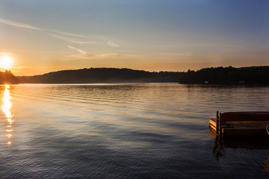 landscape of a northern lake at sunset wooden deck Canadian cottage with canoe