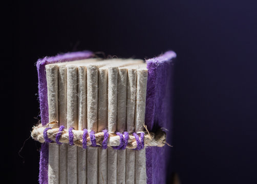 Closeup on the stitched binding of hand-made purple book