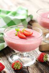 Tasty strawberry mousse in glass on brown wooden table