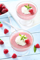 Sweet raspberry mousse in glass on blue wooden table