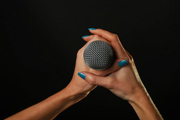 Woman hands with microphone isolated on black