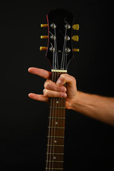 Hand with guitar and devil horns isolated on black