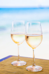 two glasses of chilled white wine on table near the beach