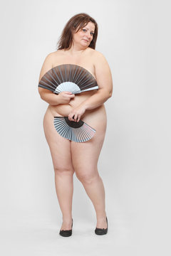Retro style picture of an naked overweight woman with folding fan.