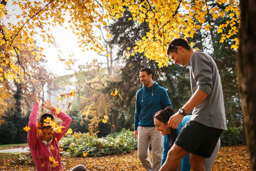 Young group of friends ,making fun at the park and throw leaves at each other.