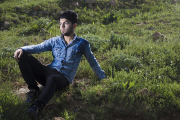 Naklejka na ściany i meble Iraqi boy in Countryside sitting on rock inside bush