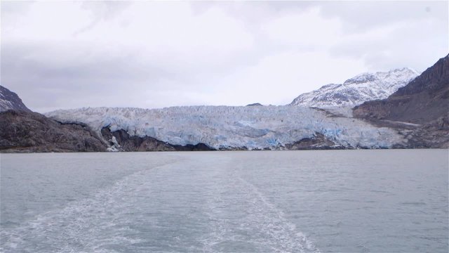 Slow motion traveling shot of a cruise ship driving away from glacier in Greenland. Slow Motion