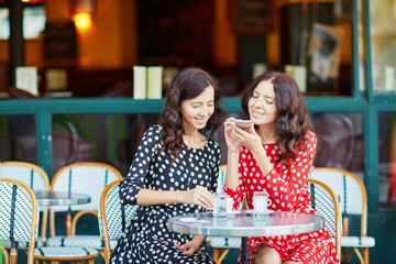 Beautiful twin sisters drinking coffee