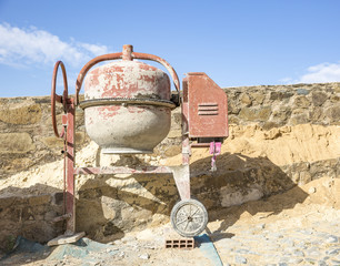 an electric cement Mixer on the floor and a blue sky
