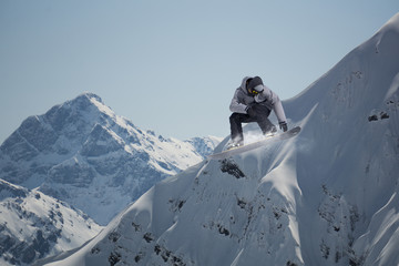 Flying snowboarder on mountains. Extreme sport.