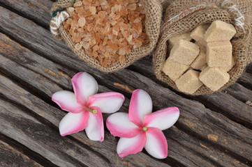Sugar and Plumeria flower on hemp sackcloth with the old wood background.Selective focus with shallow depth of field.
