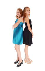 Two girls in dresses standing back to back.