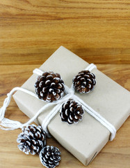 christmas present with pine cone on wooden background
