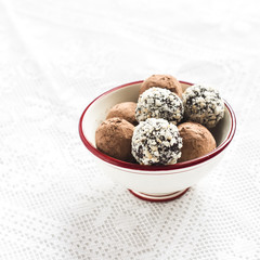 Assorted homemade dark chocolate truffles in a white ceramic bowl on a light surface