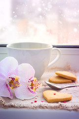 Hearts, cookies, orchid and a cup of coffee on the window sill. 