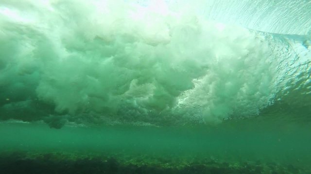  Slow motion underwater view of surfing wave breaking over coral reef in Bali, Indonesia 