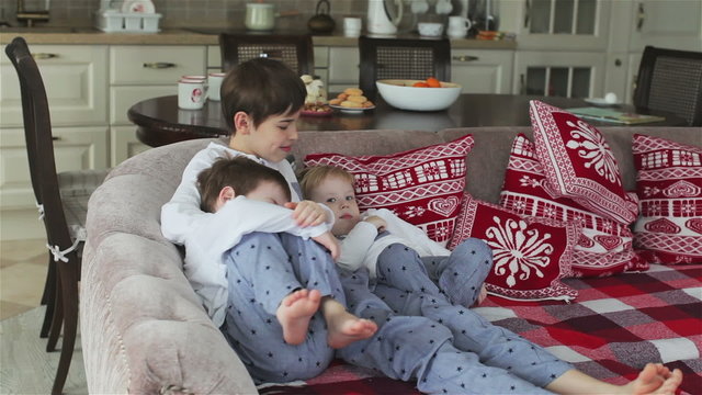 three brothers in pajamas sitting on the couch in the dining room