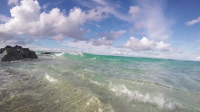 Wave breaking onto tropical beach and splashing on lens, slow motion 