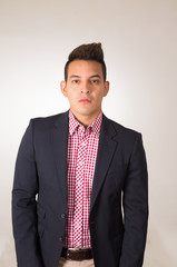 Hispanic male wearing shirt and blazer jacket standing with hands in jeans pocket empty background