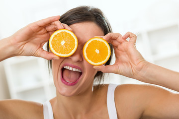 Woman holding oranges in front of her eyes