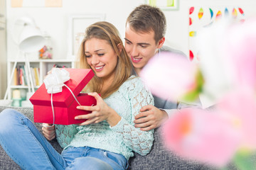 Young beautiful girl opening a present form her boyfriend