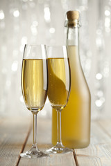 Two glasses and bottle of champagne on shining background