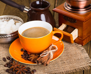 Coffee cup and coffee beans on a wooden table and sack backgroun
