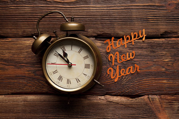 Happy new year - alarm clock on wooden background