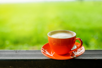 orange coffee cup with nature bokeh background.
