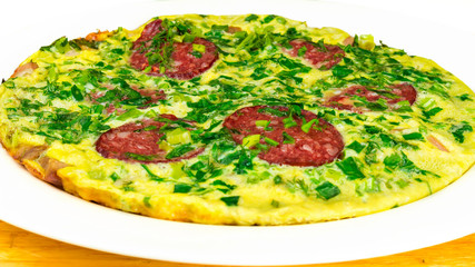 Omlete with sausage and herbs in white plate on wooden table, selective focus, close-up