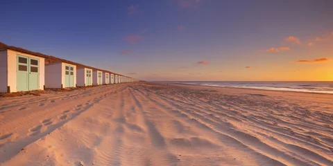 Poster Row of beach huts at sunset, Texel island, The Netherlands © sara_winter