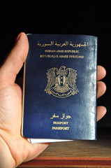 Close up of man's hand holding passport of Syrian Arab Republic