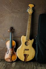 Fototapeta na wymiar Acoustic guitar and violin resting against an old steel background
