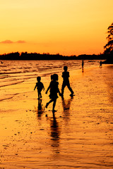 Silhouette of children playing on the beach at sunset
