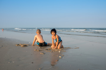 Thai brother and sister ages 8 and 6 have fun on the beach