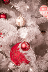 Closeup of red bauble hanging from a decorated Christmas tree