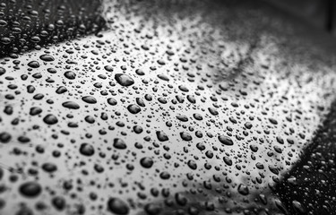 Black shining metallic car hood with raindrops