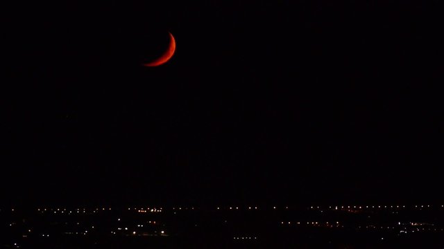 Tramonto di un quarto di luna rossa in citt&agrave;