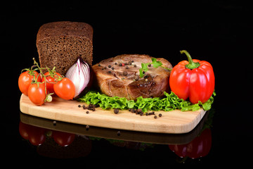 Meat medallion with vegetables on a wooden cutting board