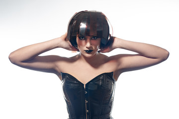 Beautiful stylish woman in leather corset and filmstrips wig isolated on white background