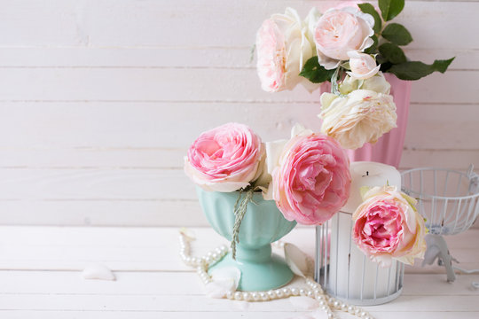 Sweet pink roses flowers in vases and candle on white painted wo